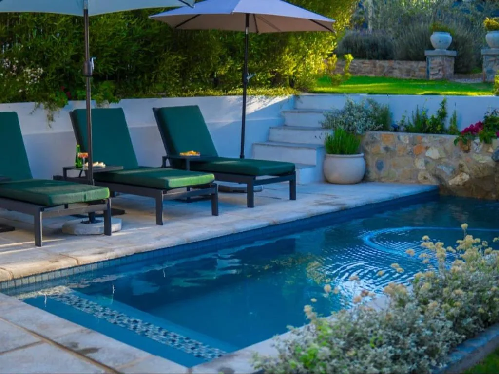 Swimming pool with loungers, umbrellas, and manicured garden surrounds