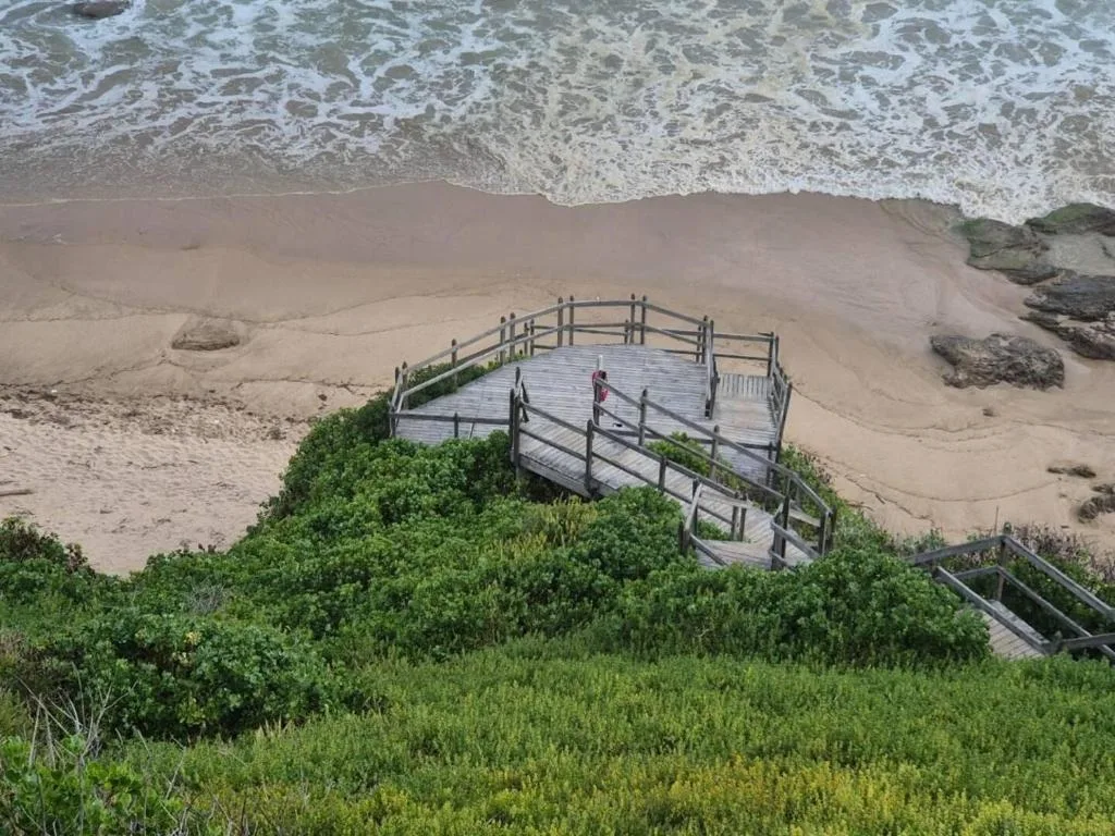 Wooden deck pathway leading to pristine beach with crashing ocean waves