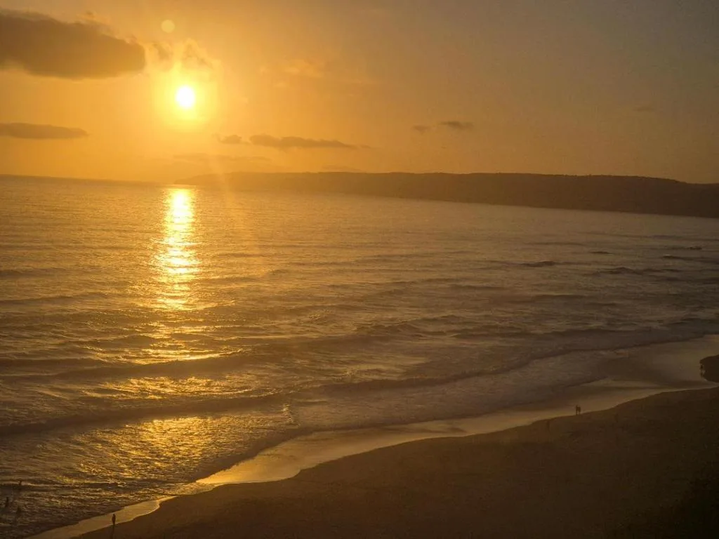 Golden sunset over the ocean with beach and cliffs visible