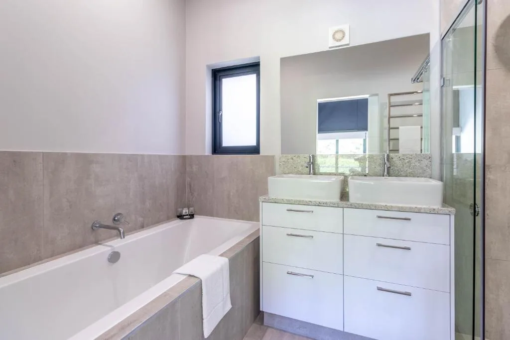 Modern bathroom with dual vessel sinks, soaking tub, and large mirror