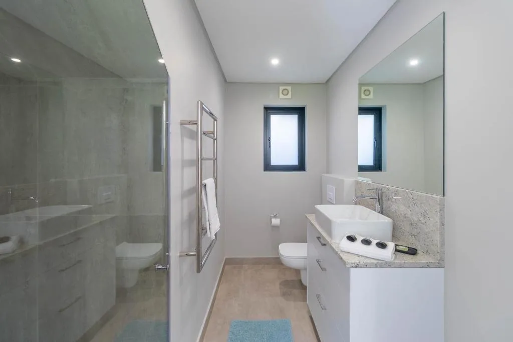 Modern bathroom with dual vanity, large mirrors, and walk-in shower