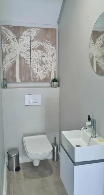 Modern bathroom with white toilet, vessel sink, and botanical wall art