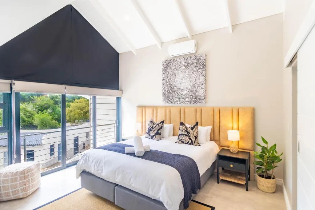 Bright bedroom with twin beds, golden headboard, and garden views from balcony doors