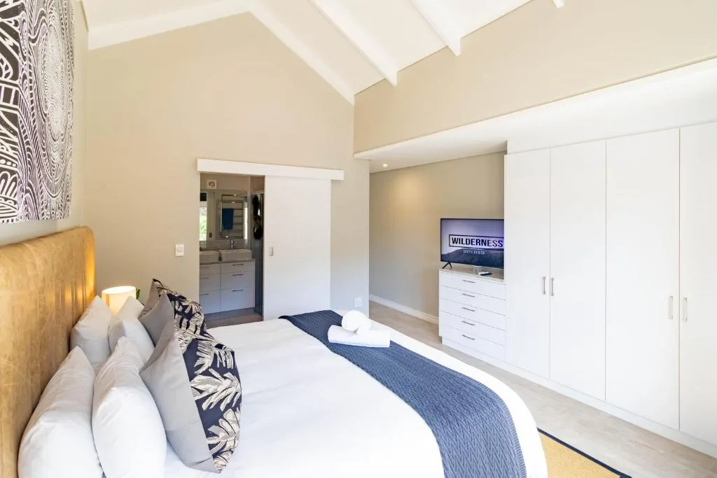 Bright bedroom with golden headboard, white linens, and ensuite bathroom view