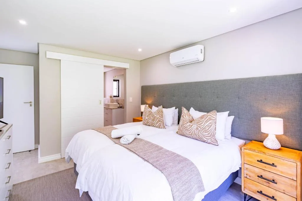 Bright bedroom with queen bed, gray headboard, and ensuite bathroom entrance