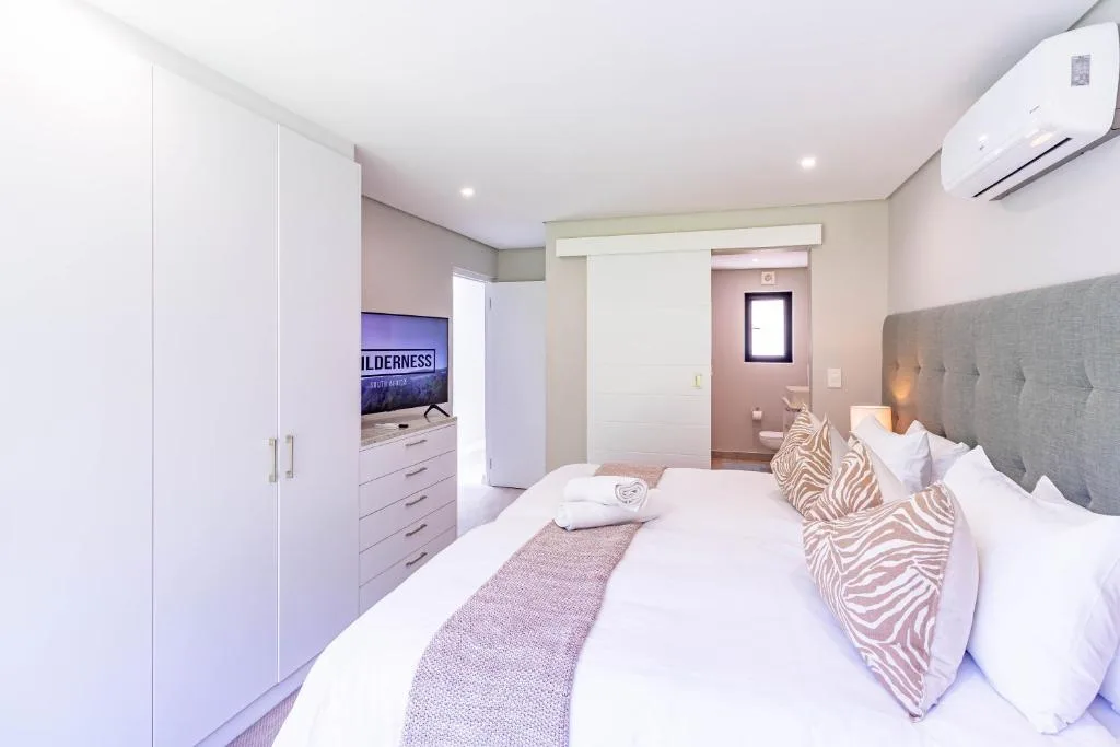 Modern bedroom with gray upholstered headboard and white fitted wardrobe