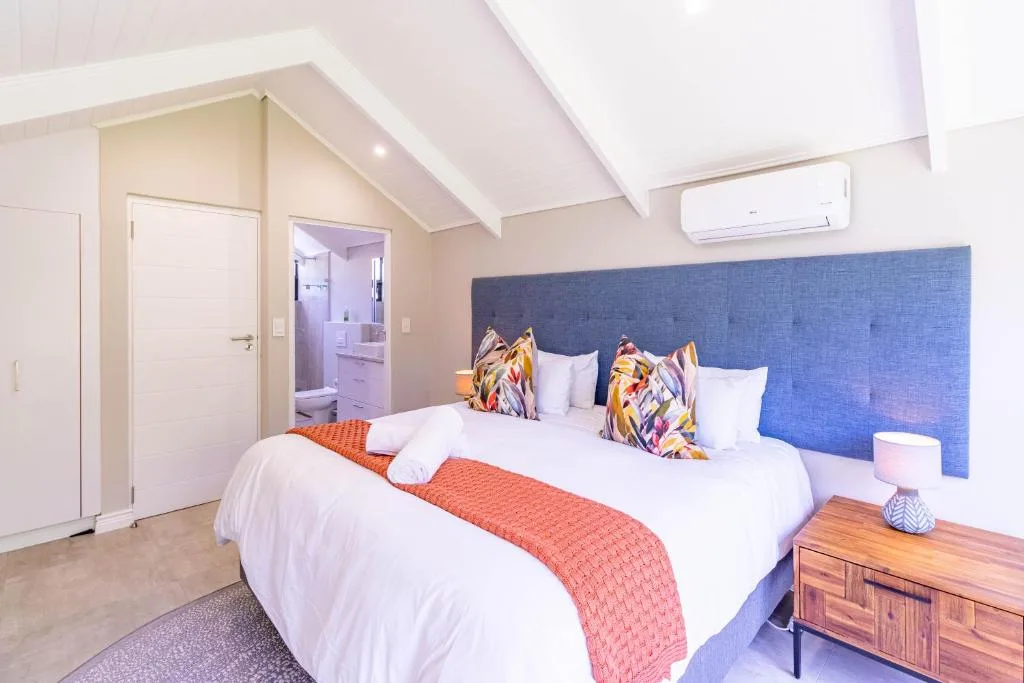 Spacious bedroom with twin beds, blue headboard, and en-suite bathroom