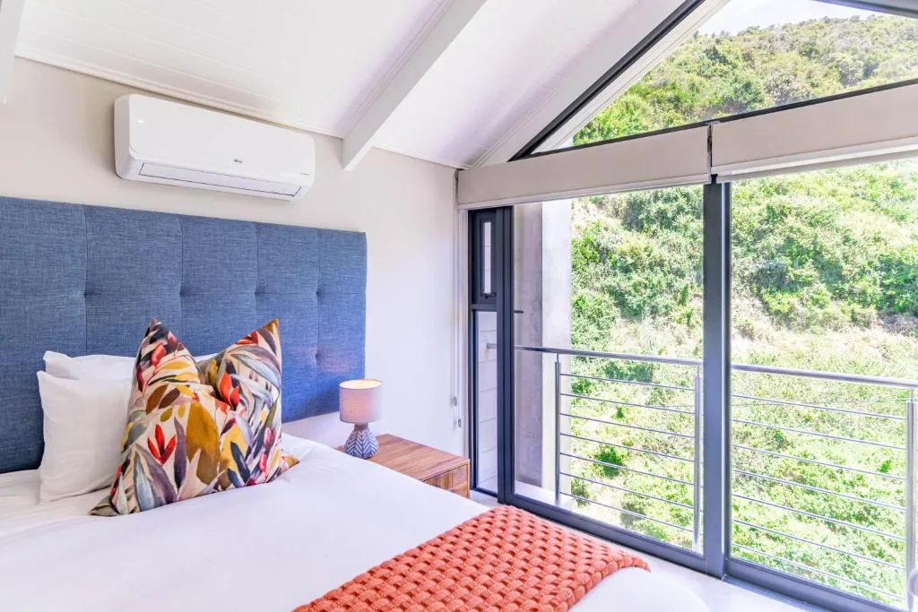 Modern bedroom with blue upholstered headboard and forest views through sliding doors