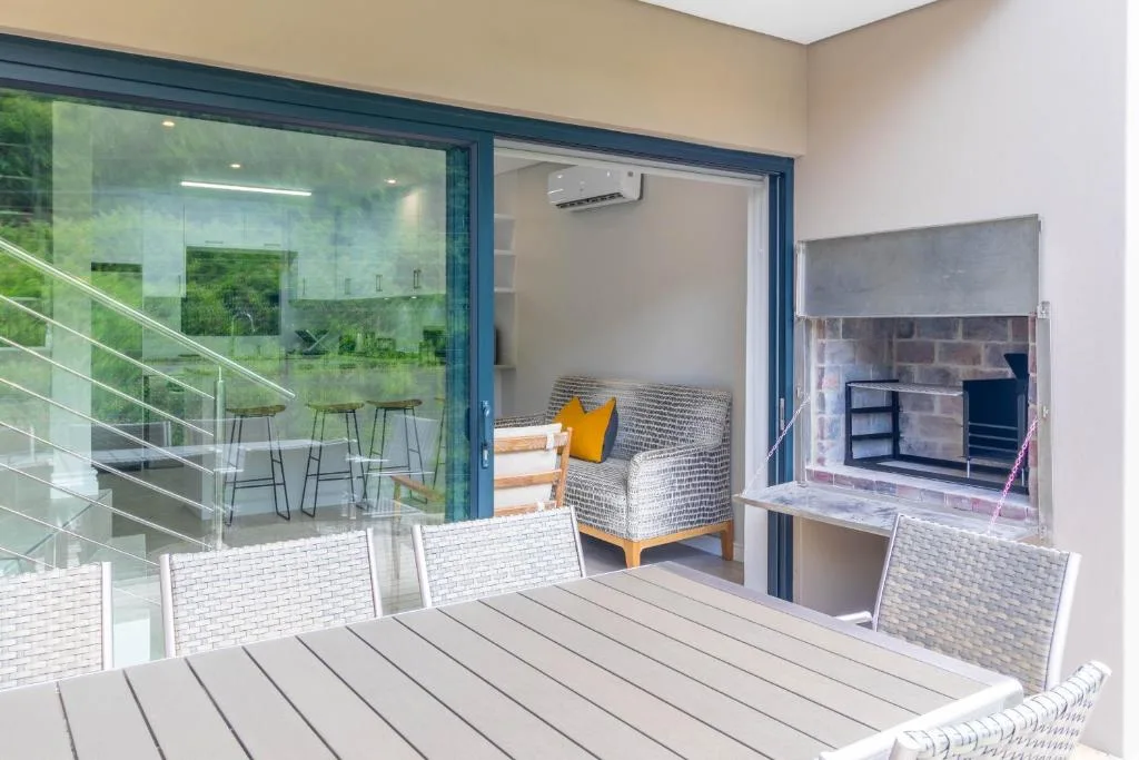 Modern wooden deck with white rattan furniture overlooking garden views