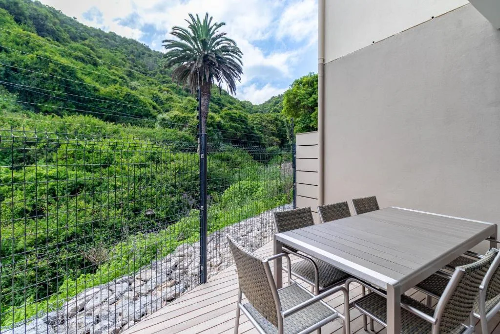 Outdoor dining deck with table overlooking lush green hillside valley