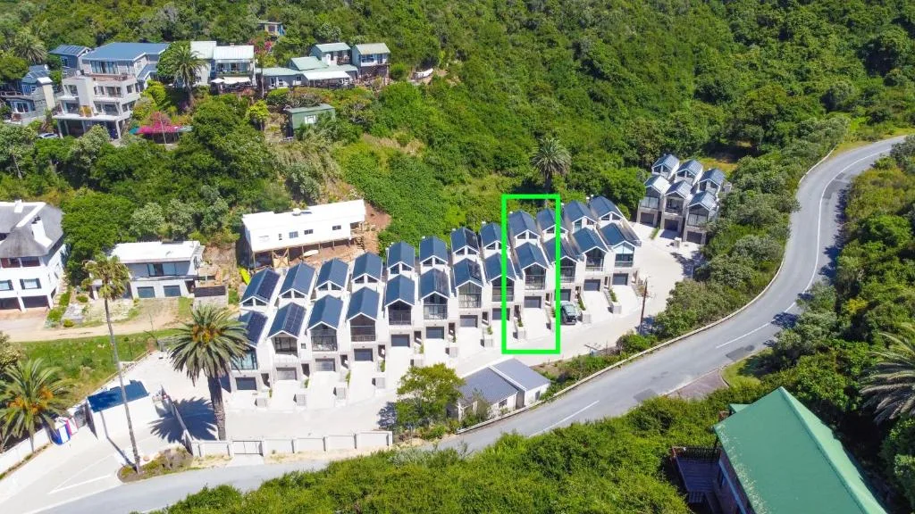 Aerial view of modern white apartment complex nestled in lush green surroundings