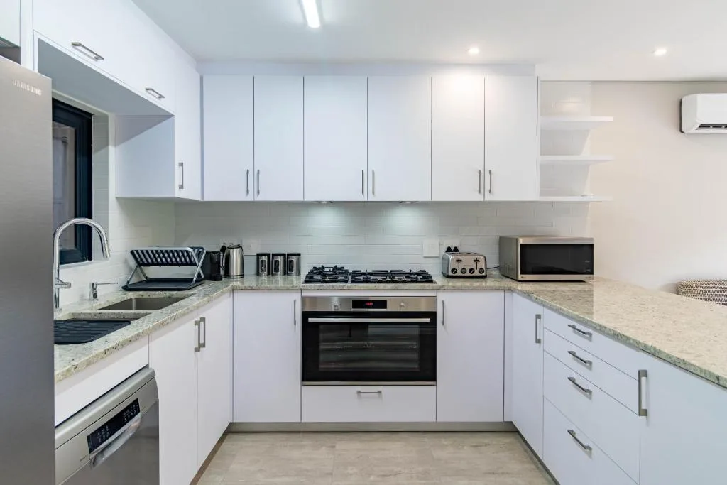 Modern white kitchen with gas stove, built-in oven, and granite countertops