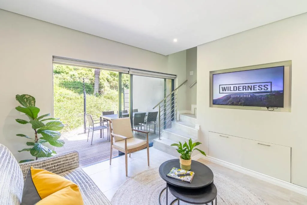 Modern lounge with sofa, armchair, TV, and sliding doors to deck