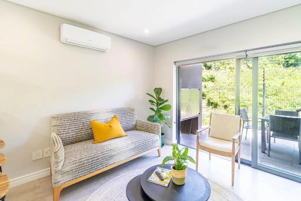 Bright lounge with patterned sofa, accent chair, and deck access overlooking greenery