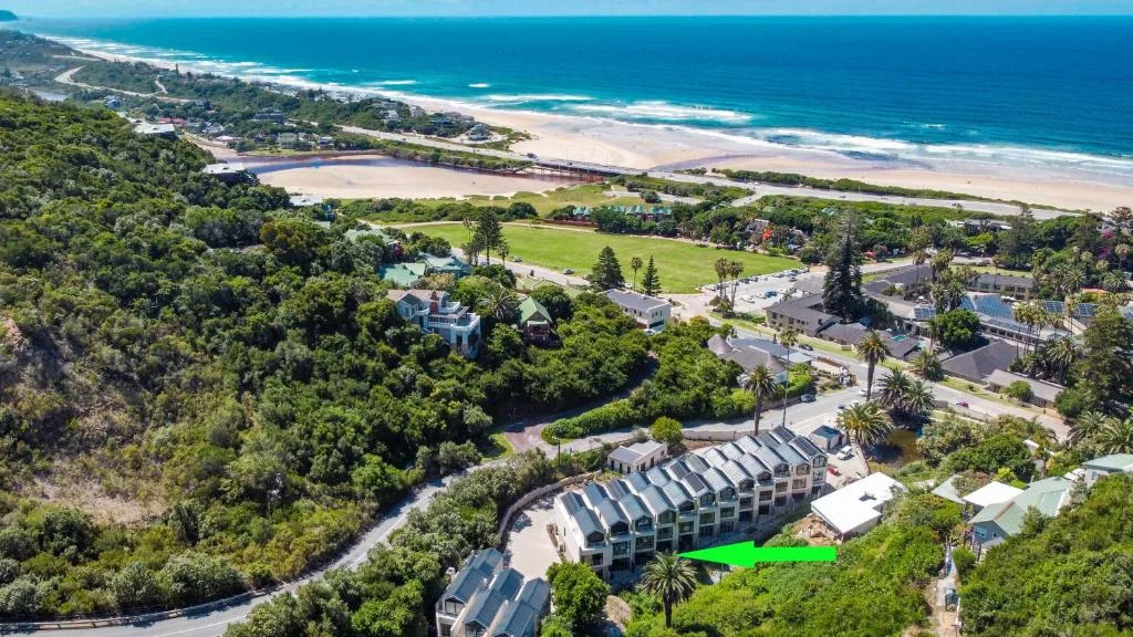 Aerial view of beachfront property with lagoon, forest and ocean beyond