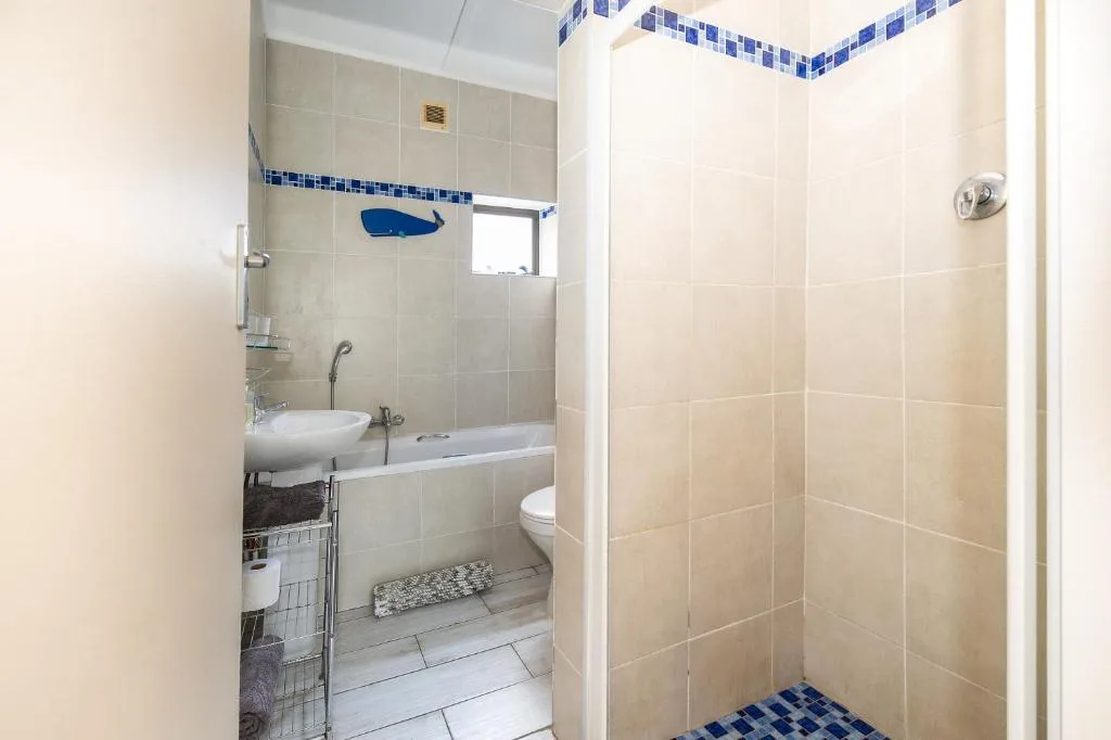 Bright bathroom with beige tiles, shower cubicle, toilet, and sink