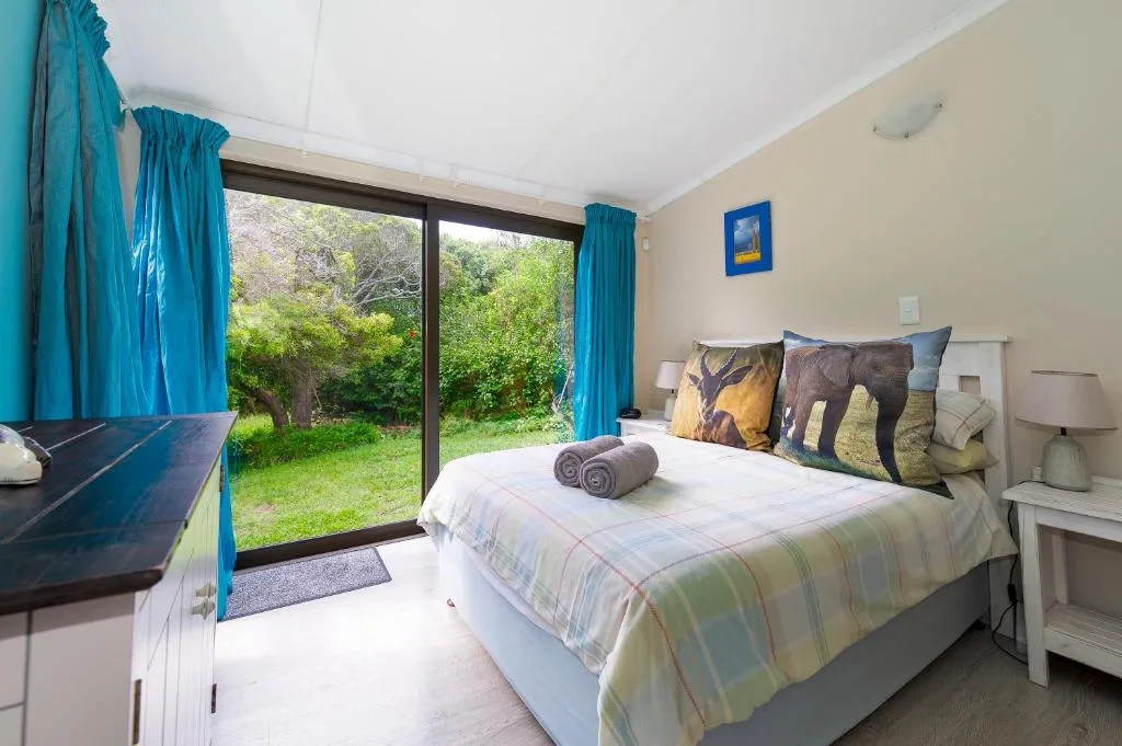 Bright bedroom with queen bed, garden views through sliding doors, turquoise curtains