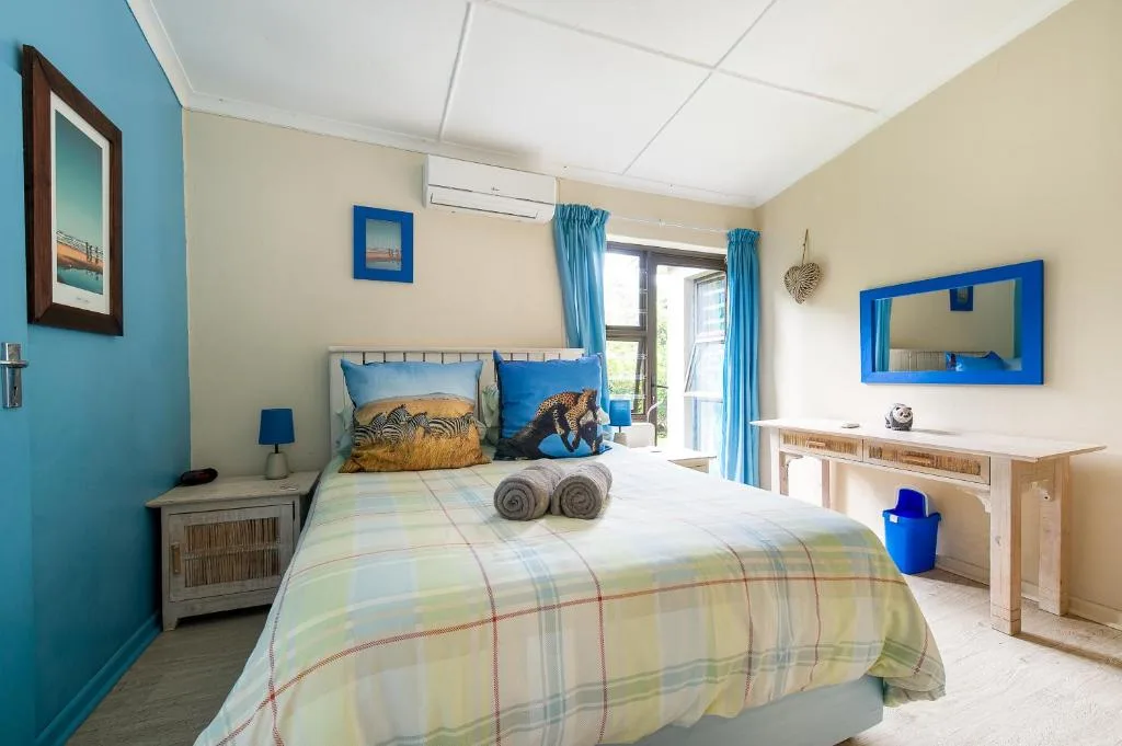 Bright bedroom with blue accent wall, comfortable bed, and garden views