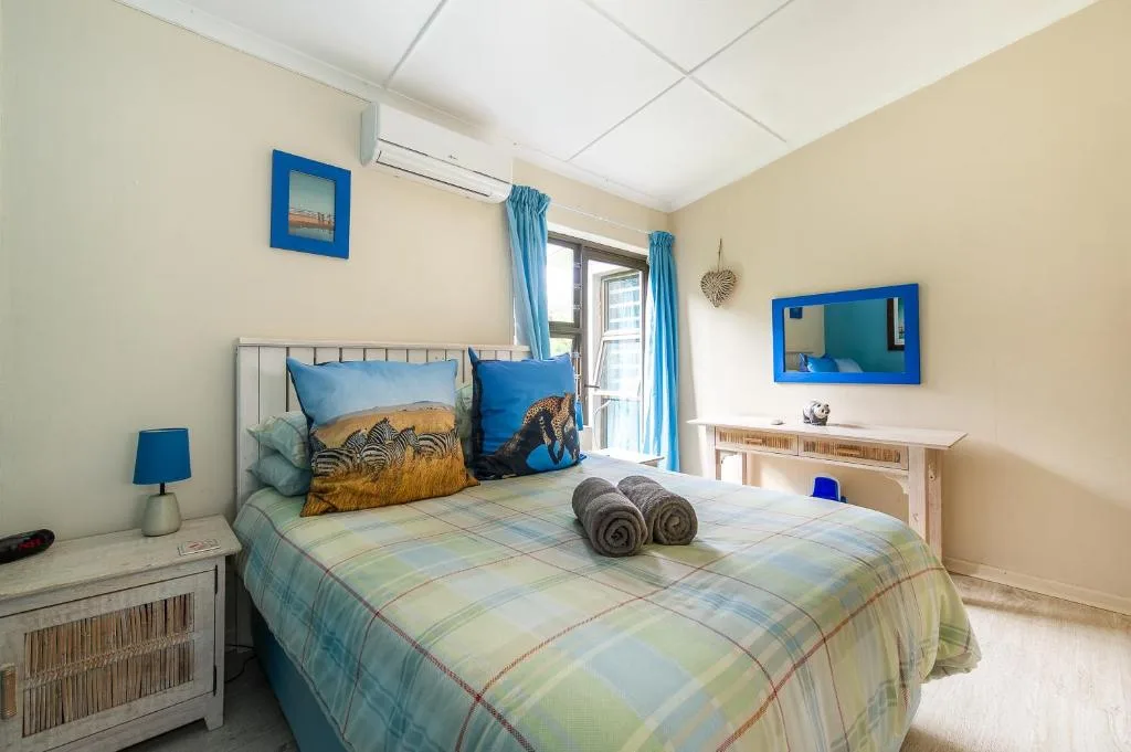 Bright bedroom with queen bed, blue wildlife pillows, and ocean view doors