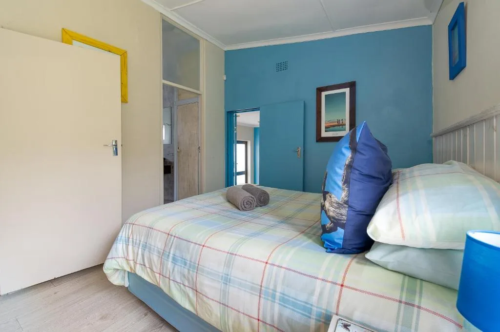 Bright bedroom with turquoise accent wall and single bed with checkered bedding