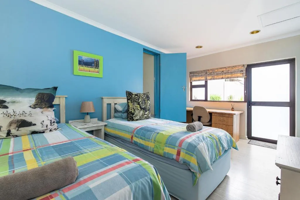 Bright blue bedroom with two beds and colorful striped bedding