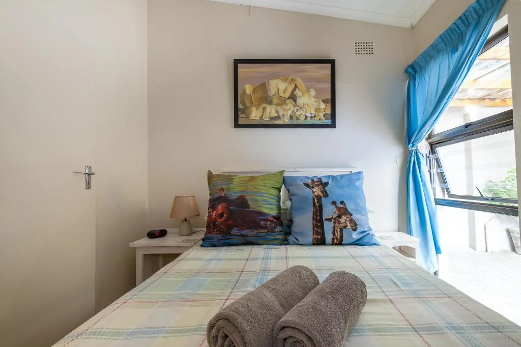 Bright bedroom with bed, rolled towels, wildlife pillows, and blue curtains