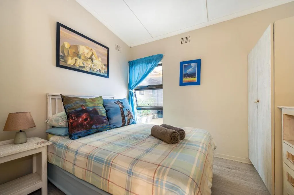 Bright bedroom with double bed, colorful pillows, and blue curtained window