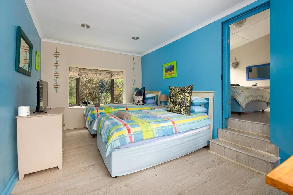 Bright blue bedroom with colorful quilted bed and garden views through windows