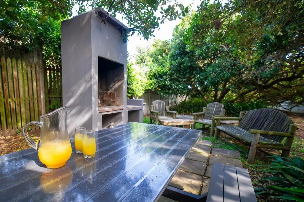 Outdoor dining area with braai fireplace and garden seating
