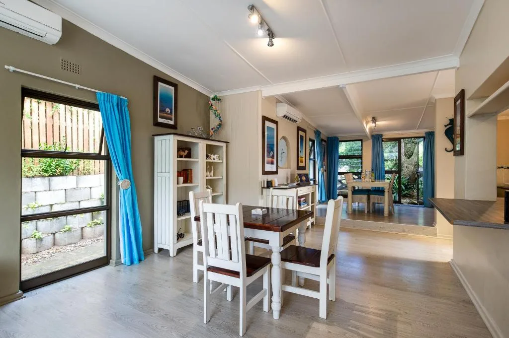 Dining table with white chairs in open-plan living area with natural light
