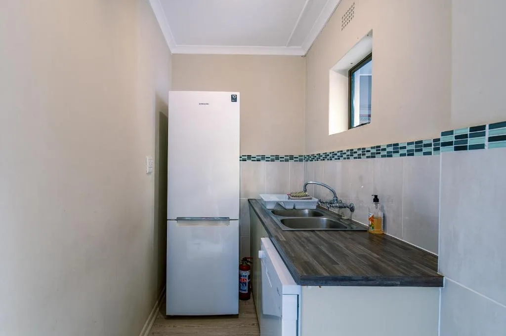Compact kitchen with white refrigerator, dark countertop, and tiled backsplash