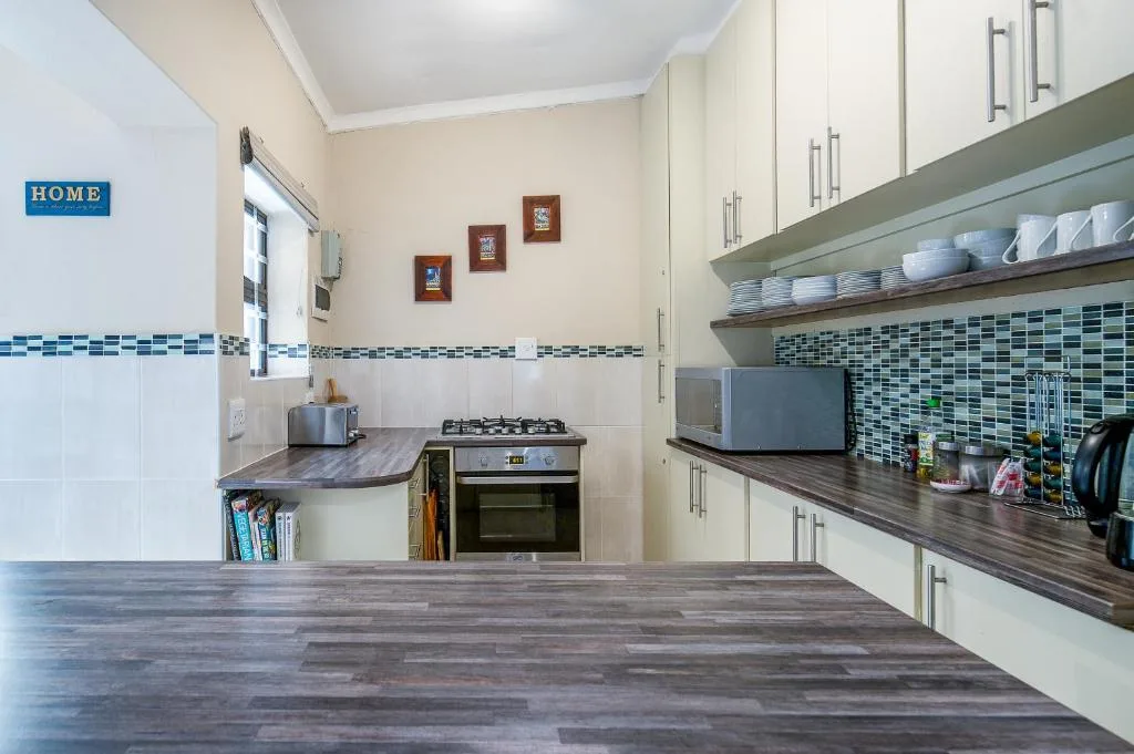 Modern kitchen with cream cabinetry, gas stove, and mosaic tile backsplash