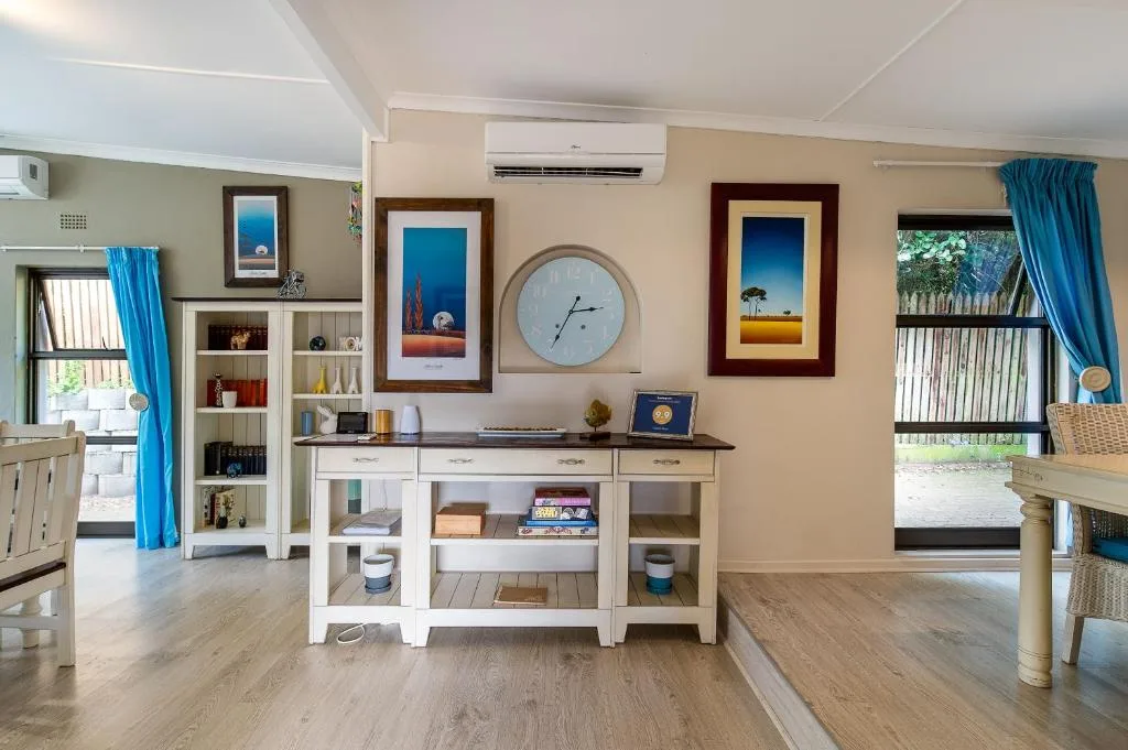 Bright lounge with white shelving, wall art, clock, and air conditioning unit