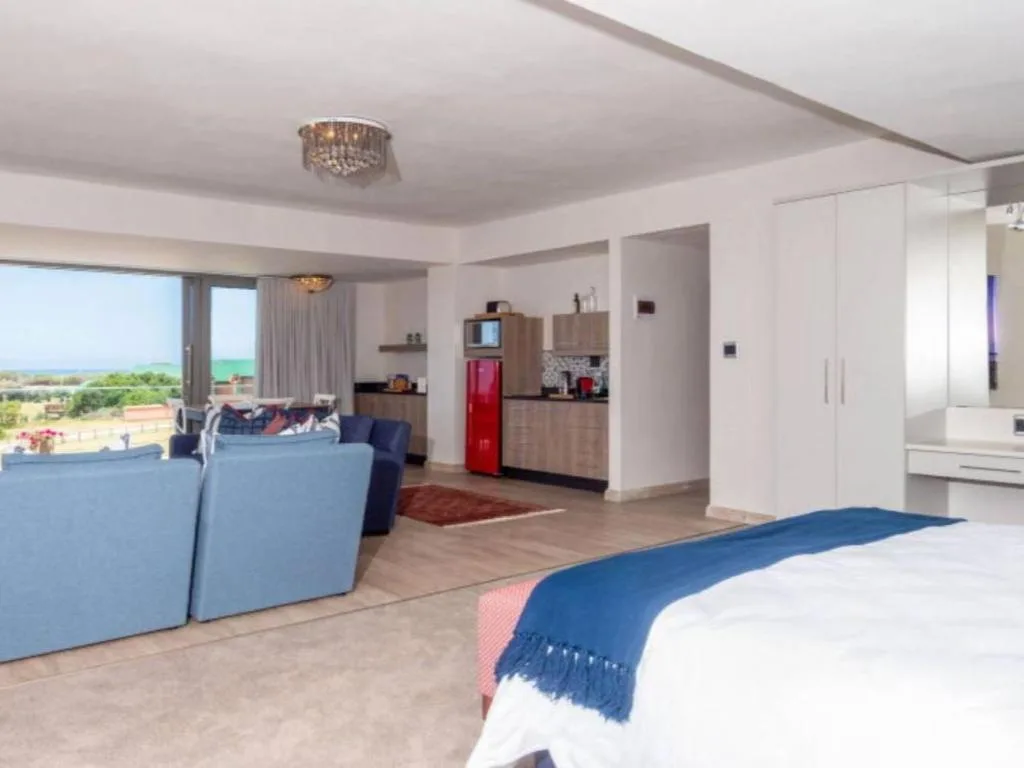 Modern bedroom with ocean view, open-plan lounge and kitchen area visible