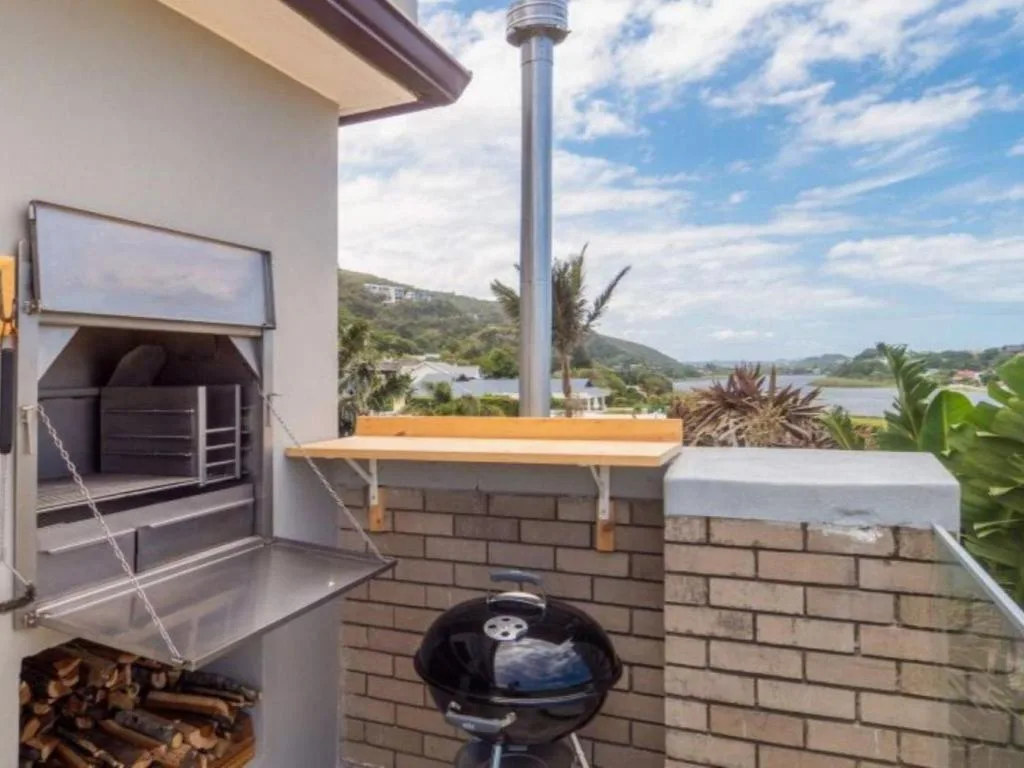 Outdoor braai area with grill and mountain lagoon views beyond
