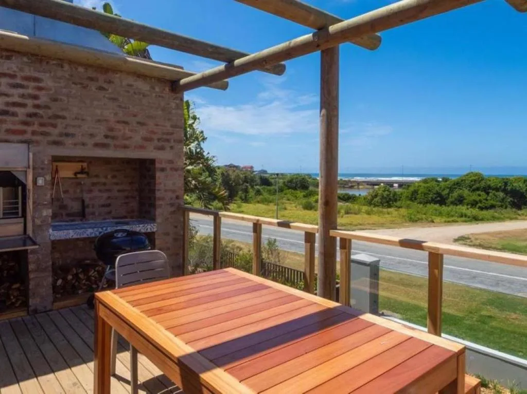 Wooden deck with pergola, dining table, braai, and coastal views