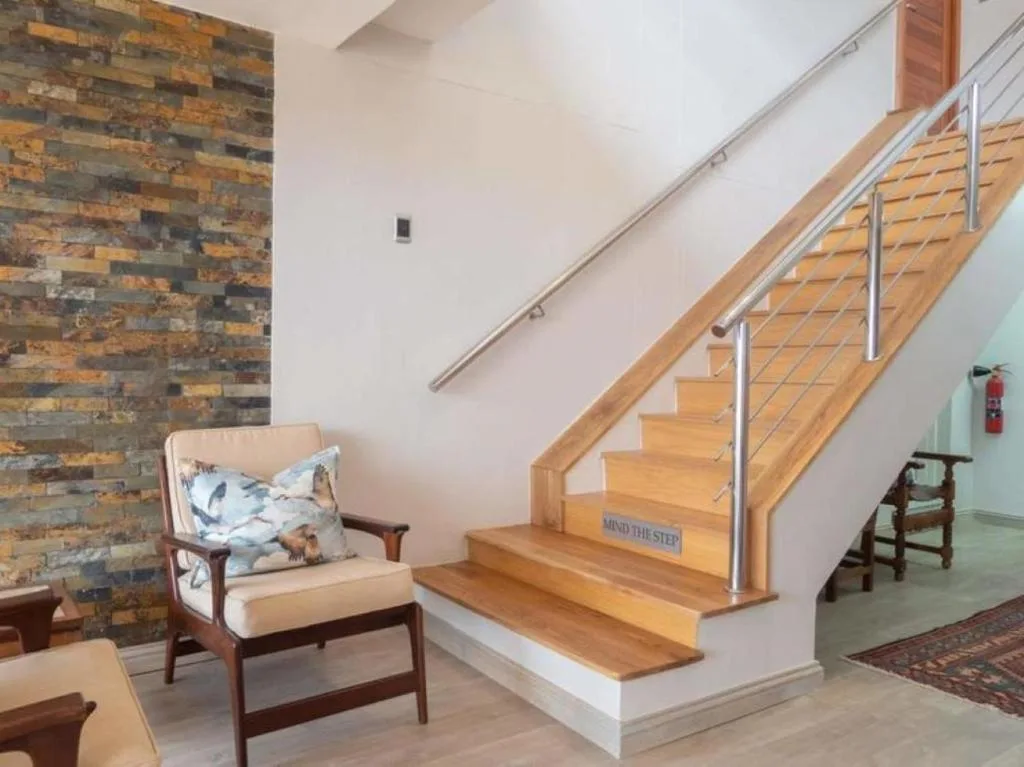 Modern wooden staircase with metal railing and mid-century armchair in bright interior space