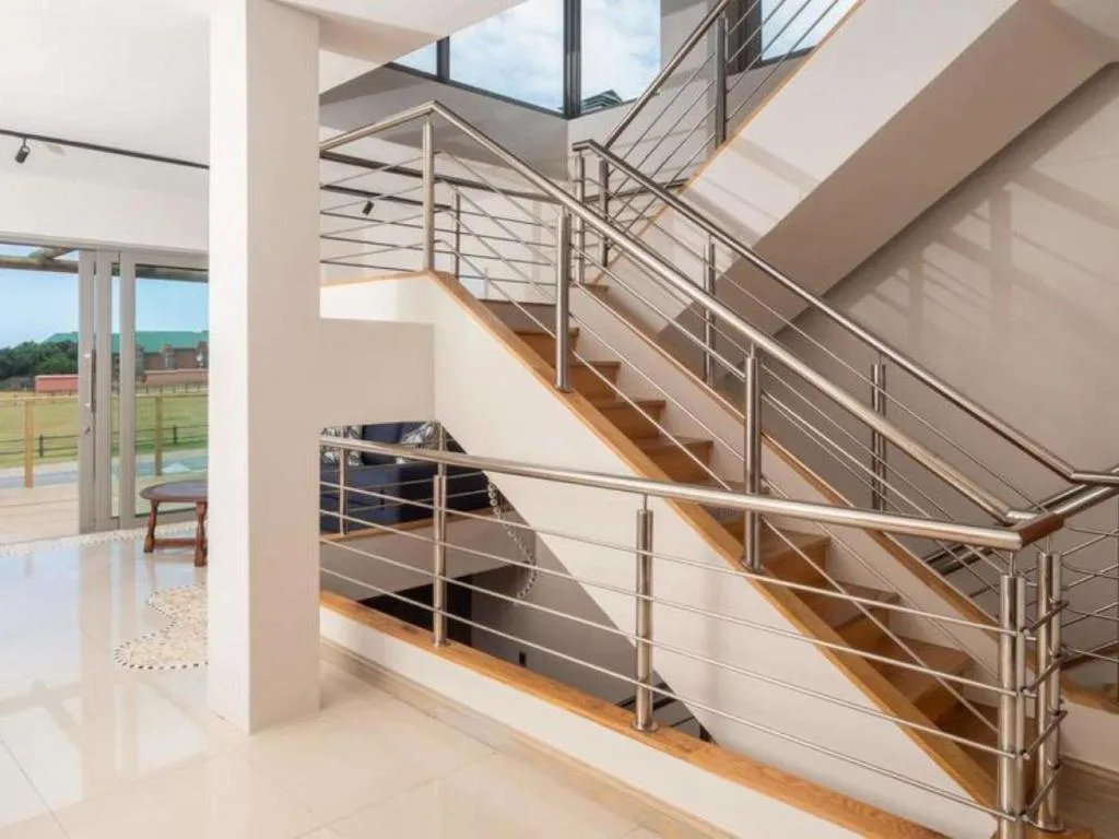 Modern staircase with metal railings and wooden steps in bright interior