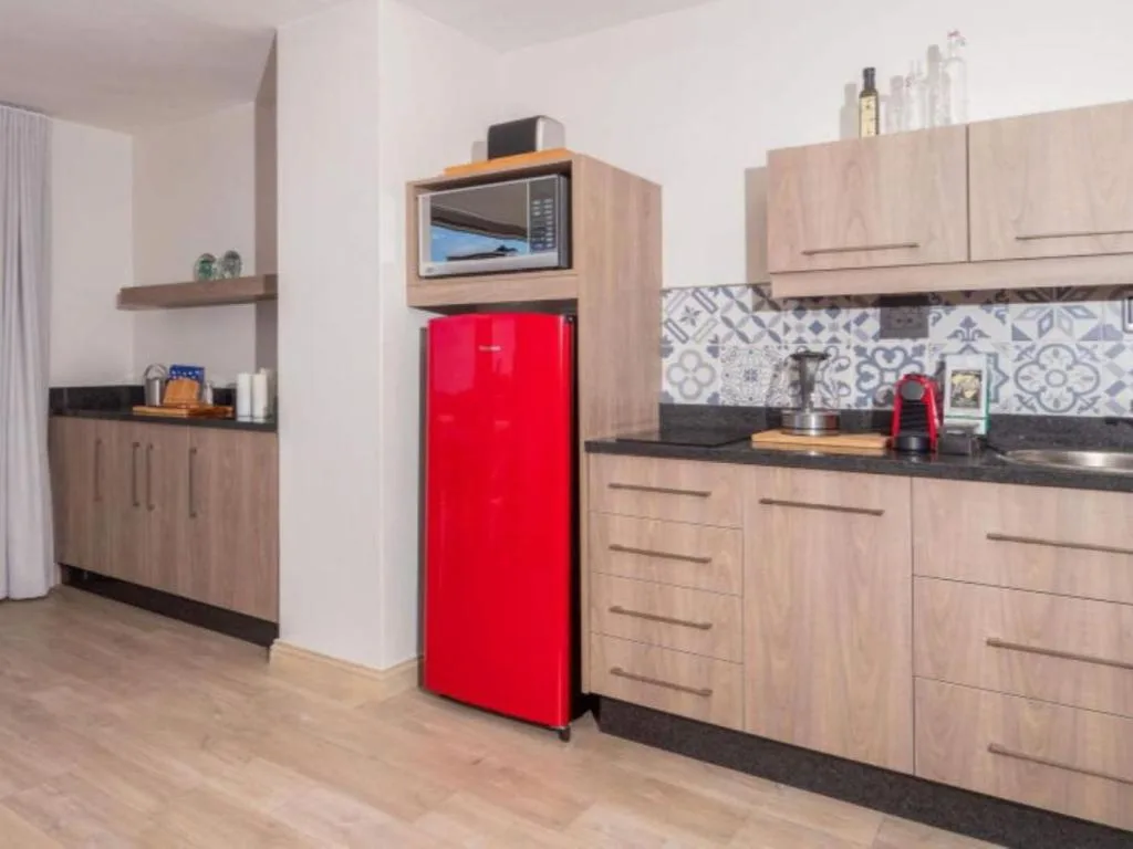 Modern kitchen with red fridge, wooden cabinetry, and patterned backtile