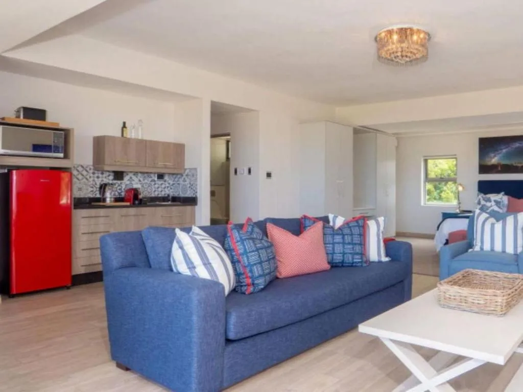 Open-plan living area with blue sofa, kitchen, and bedroom visible in background