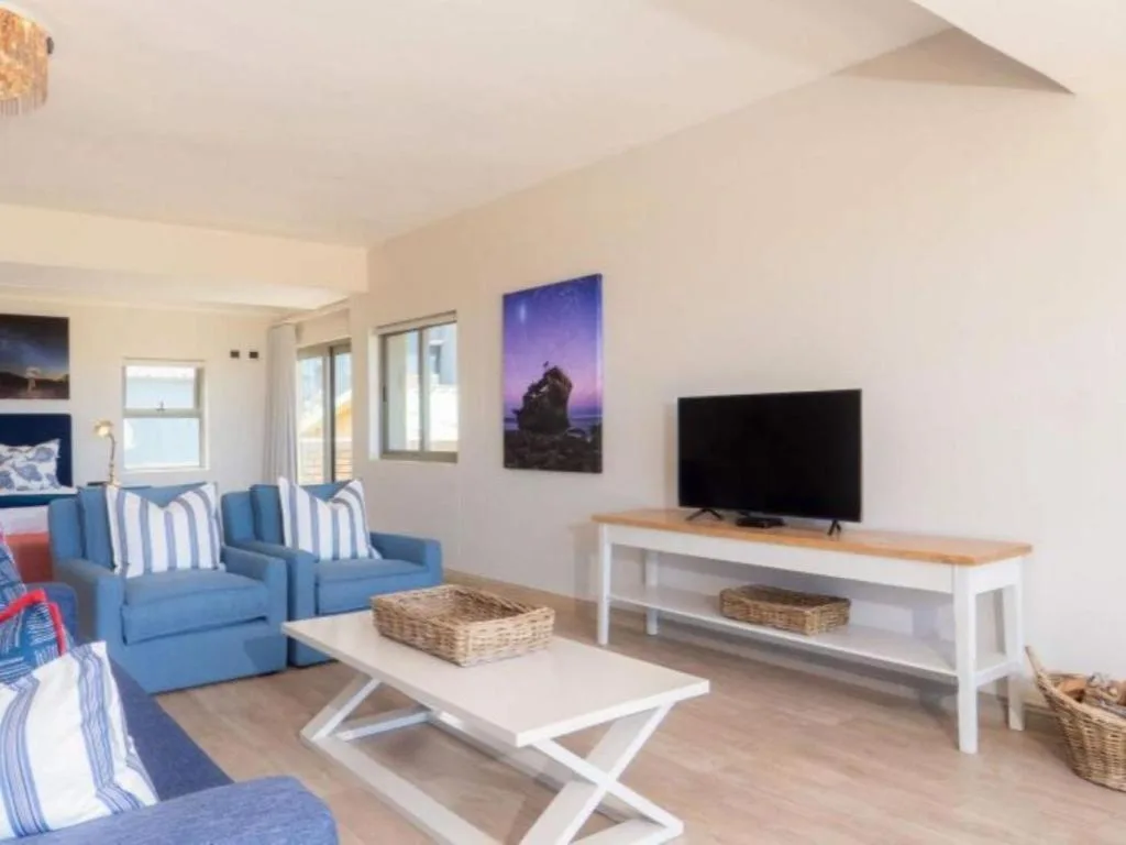 Bright lounge with blue armchairs, TV, and coastal artwork