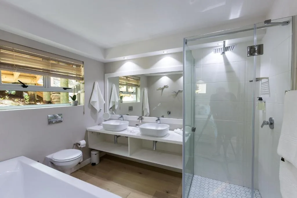 Modern bathroom with dual vanity, walk-in shower, and natural light