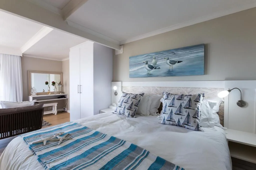 Coastal-themed bedroom with white bedding, nautical pillows, and seagull artwork