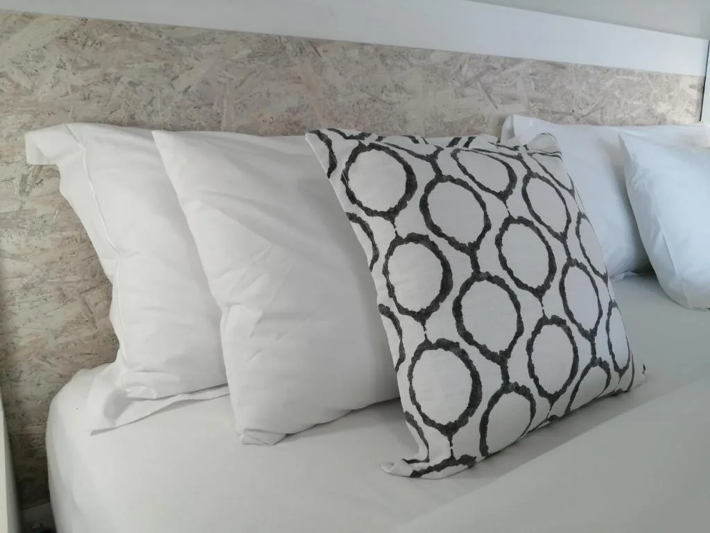 Bed with white pillows and patterned decorative cushion against stone headboard