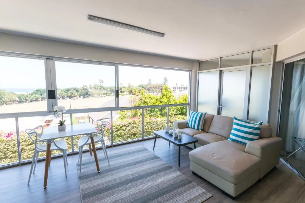 Modern covered balcony with dining table, seating, and scenic garden views