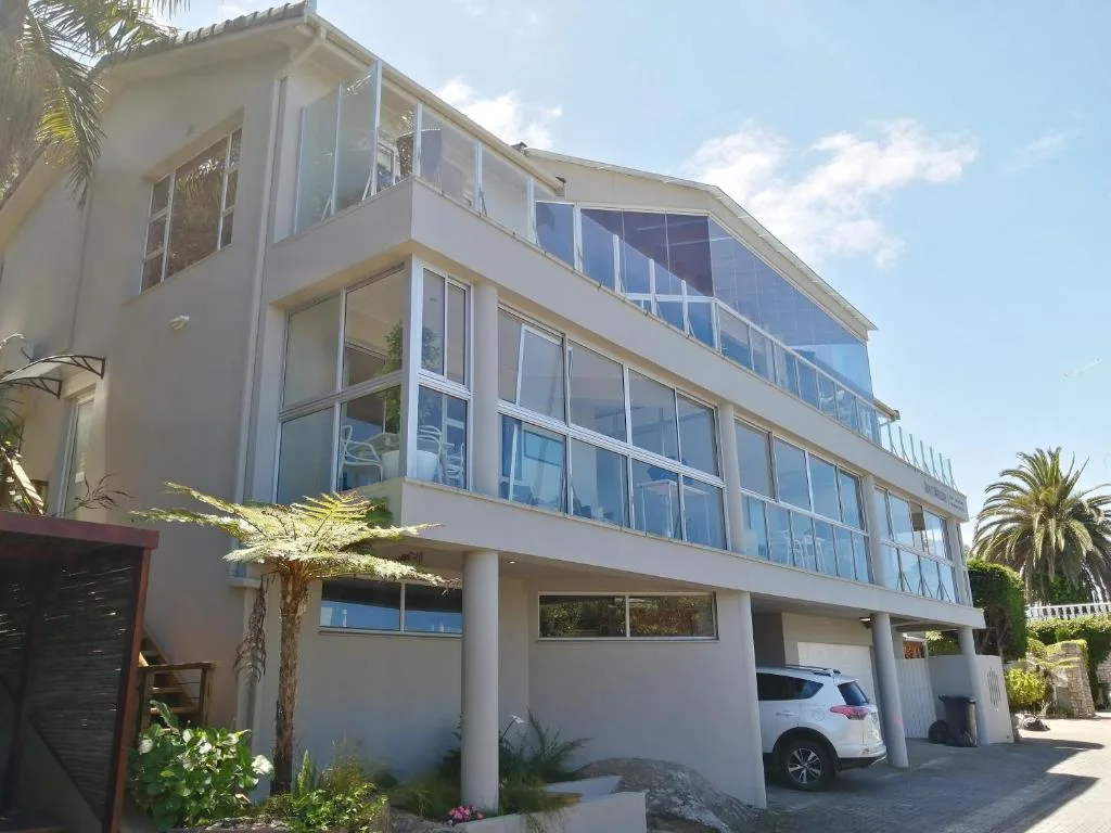Modern white multi-story building with large windows and palm trees