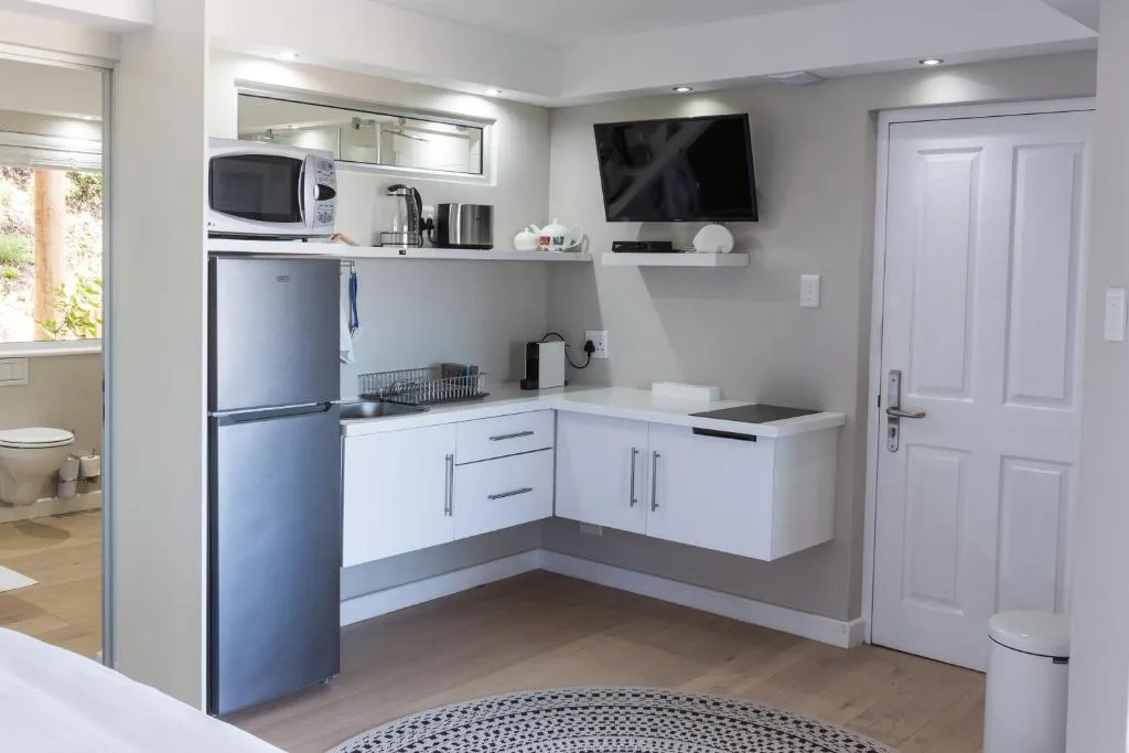 Modern kitchenette with white cabinetry, stainless steel appliances, and wall-mounted TV