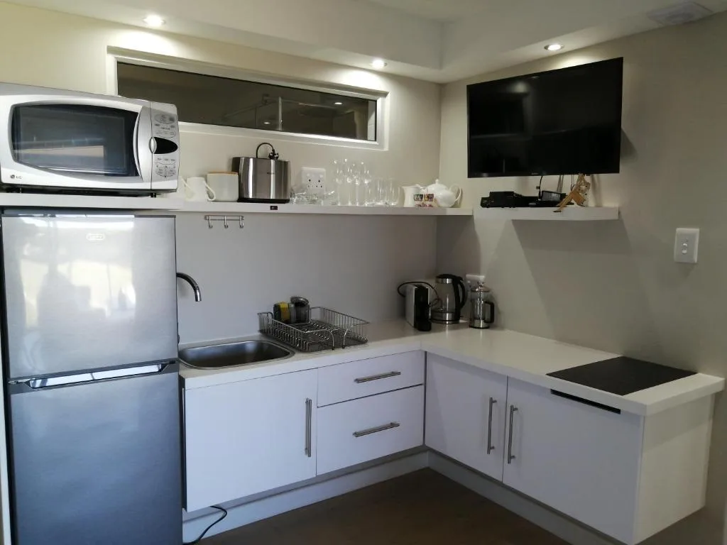 Compact kitchenette with white cabinetry, refrigerator, and microwave
