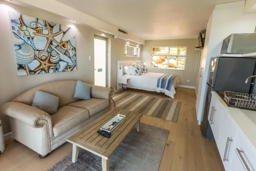 Open-plan lounge with beige sofa, coffee table, and coastal artwork