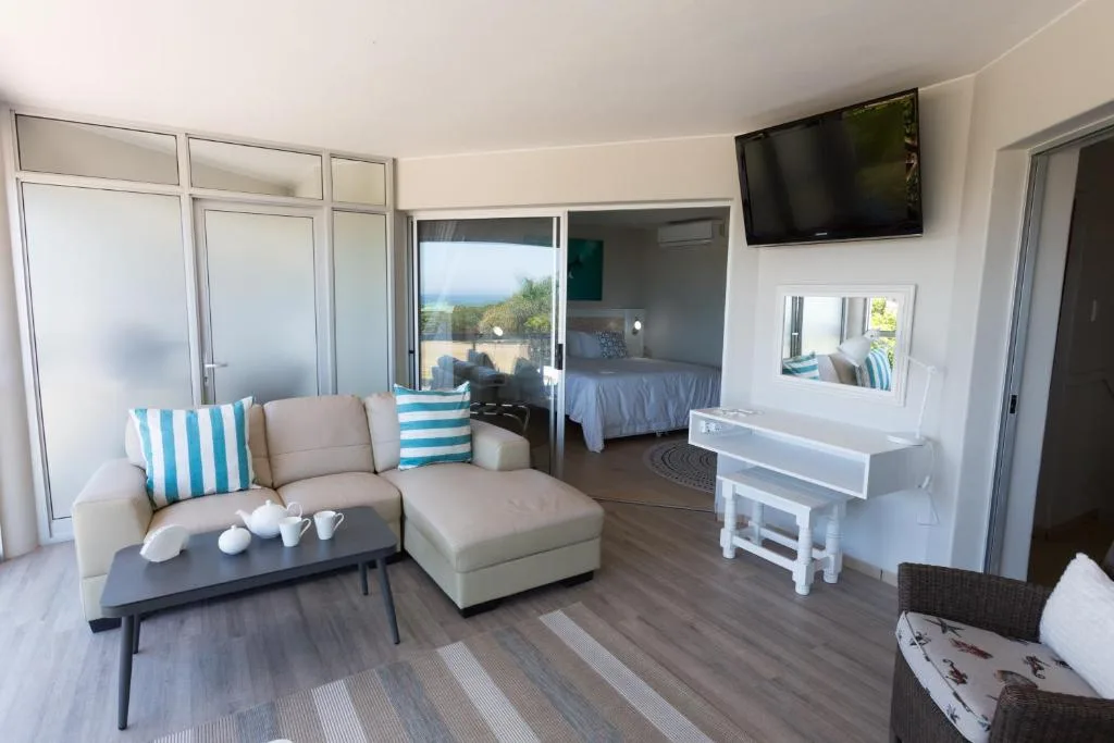 Spacious open-plan lounge with beige sofa, ocean view, and TV